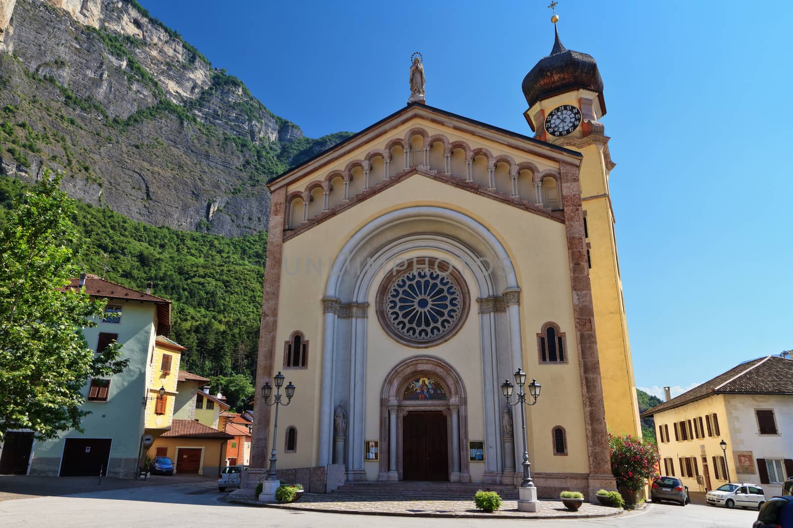 church in Mezzacorona village on sunny summer day with mountains in the background, Trentino, Italy