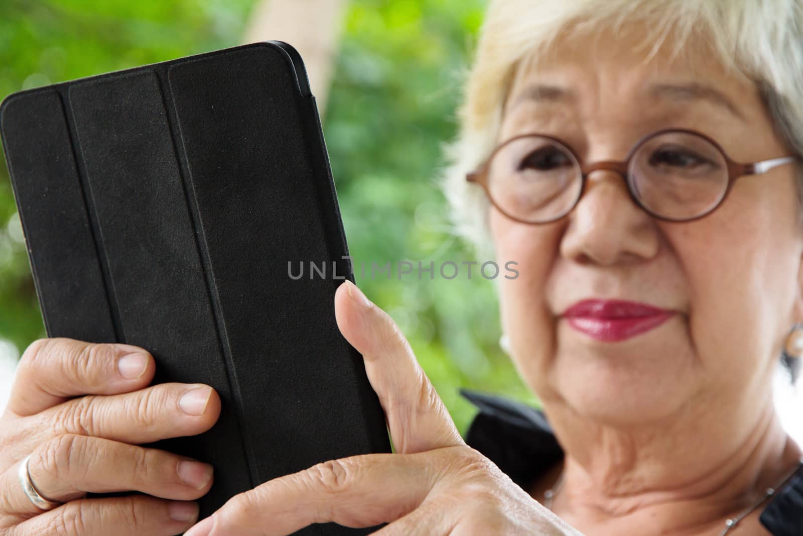 Senior women relaxing at home reading E-book on her tablet.