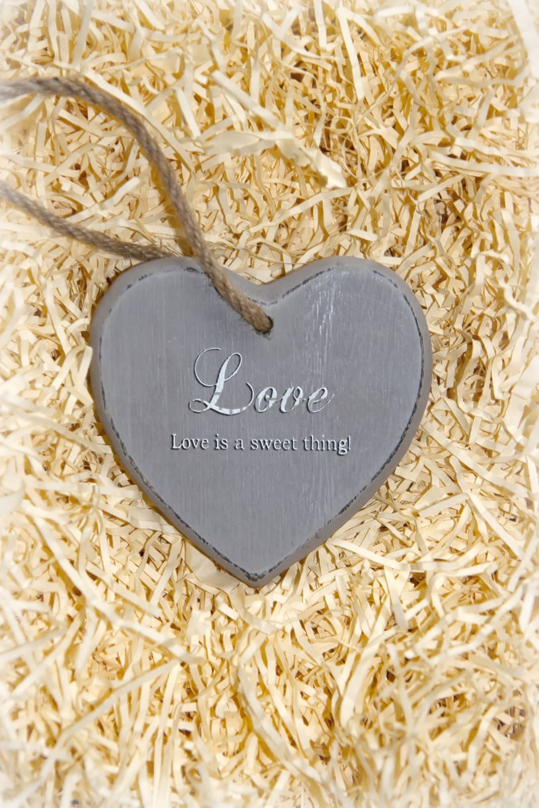 single grey wooden love heart in a love nest made of straw inscribed love is a sweet thing