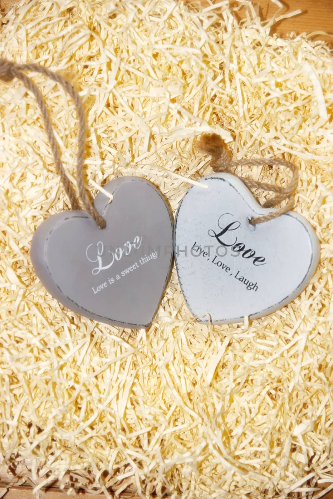 two grey wooden love hearts in a love nest made of straw with loving inscriptions