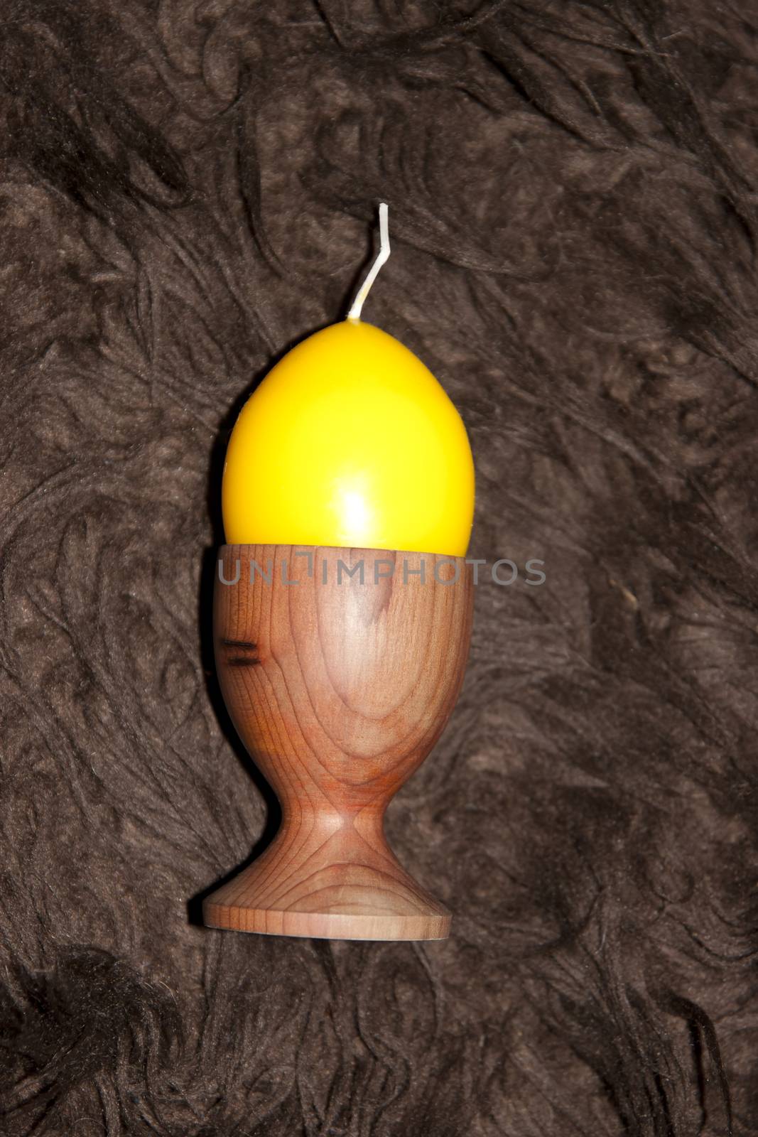 unlit yellow egg shaped candle in an egg cup