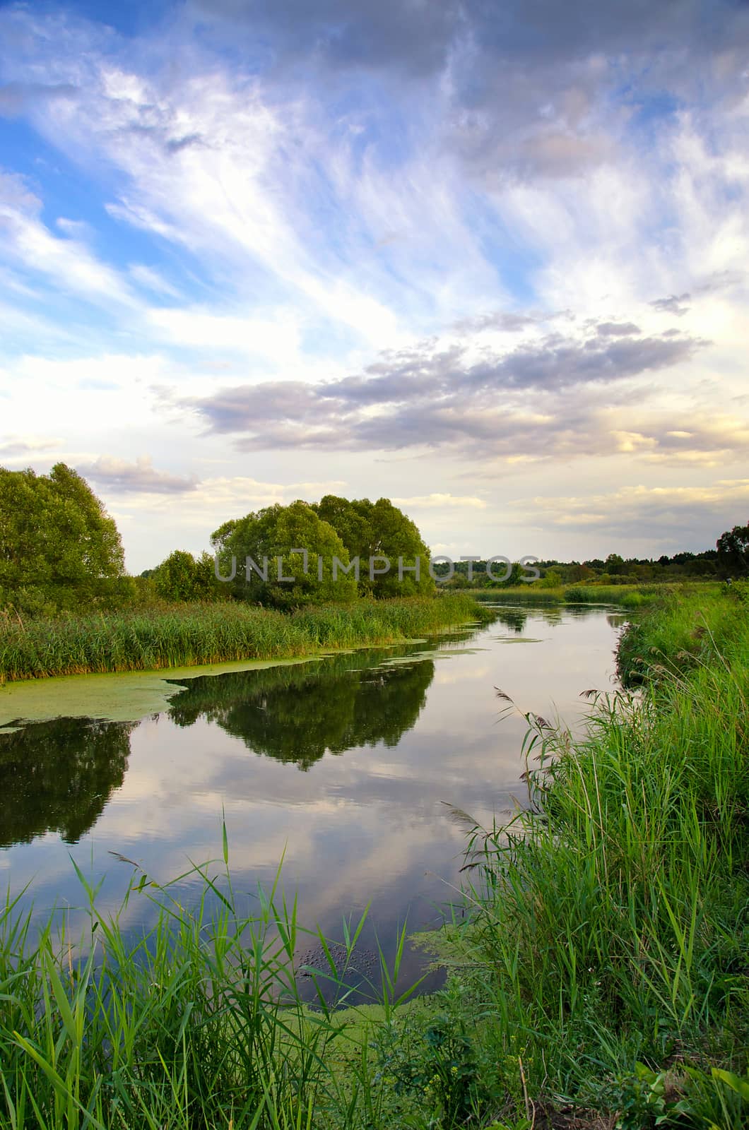 Summer landscape with the sky and clouds reflecting in the surface of the  river