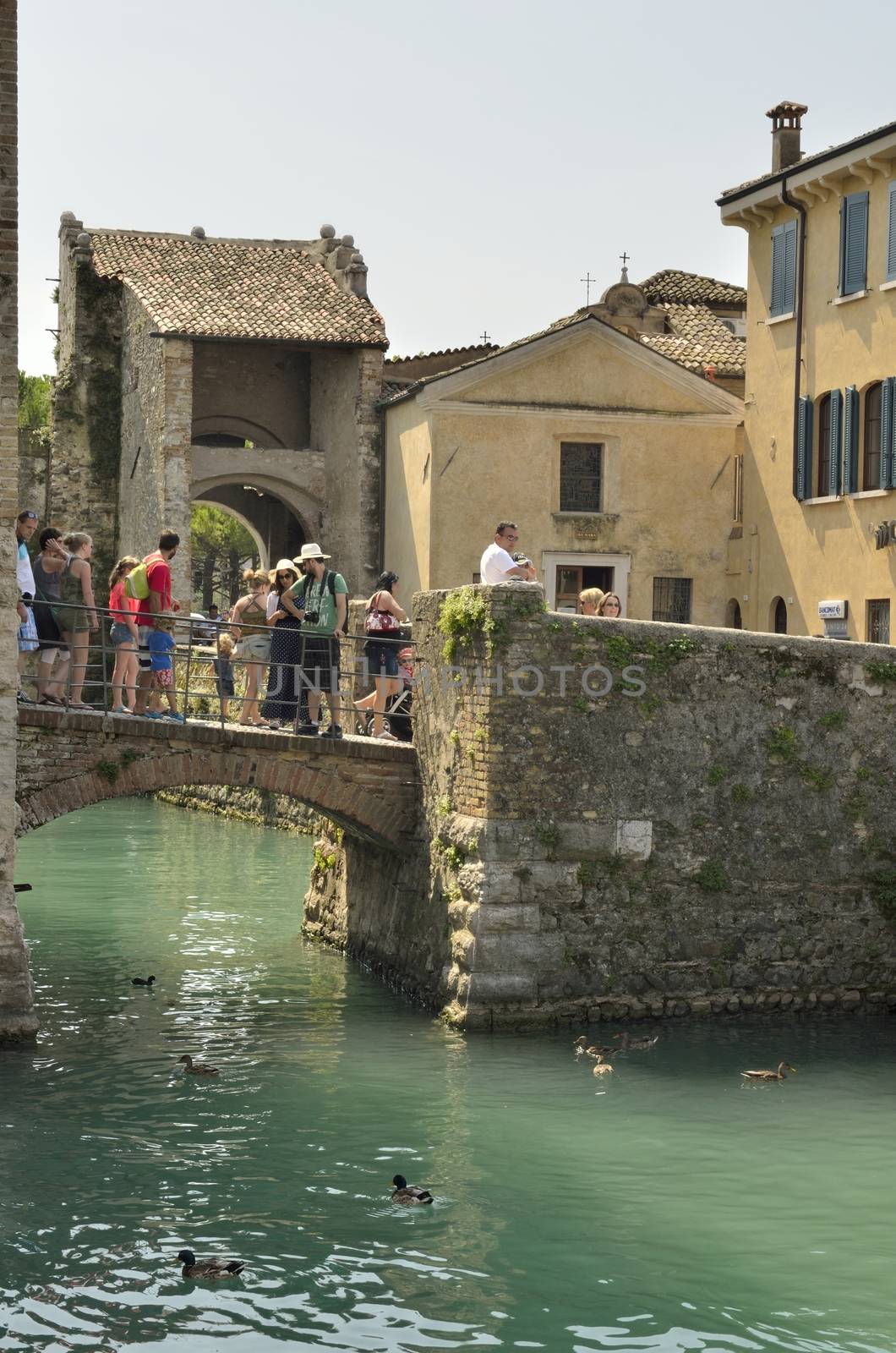Tourists over a bridge in Sirmione on lake Grada, Italy. 