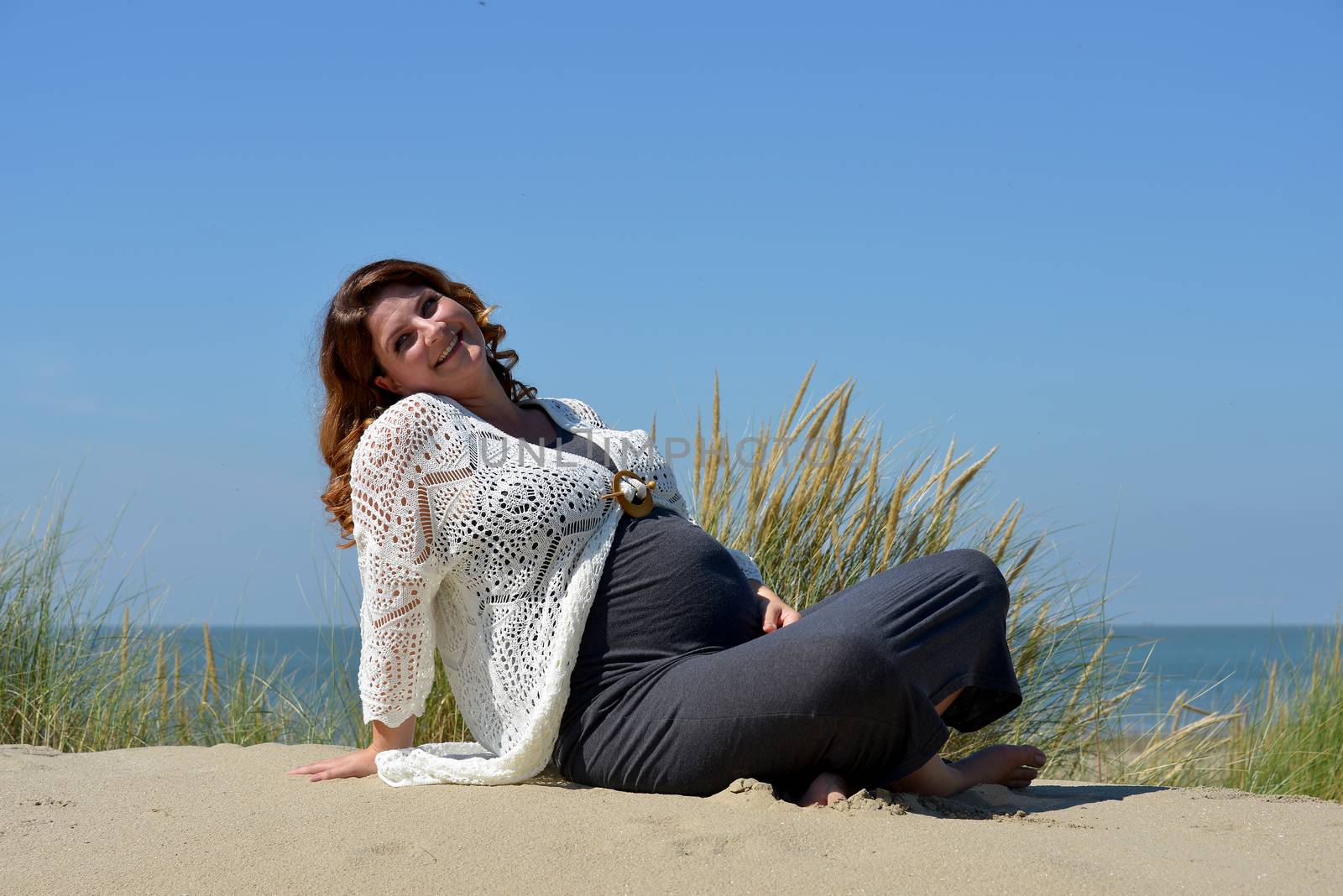 pregnant woman happy and smiling on the beach with sea as background