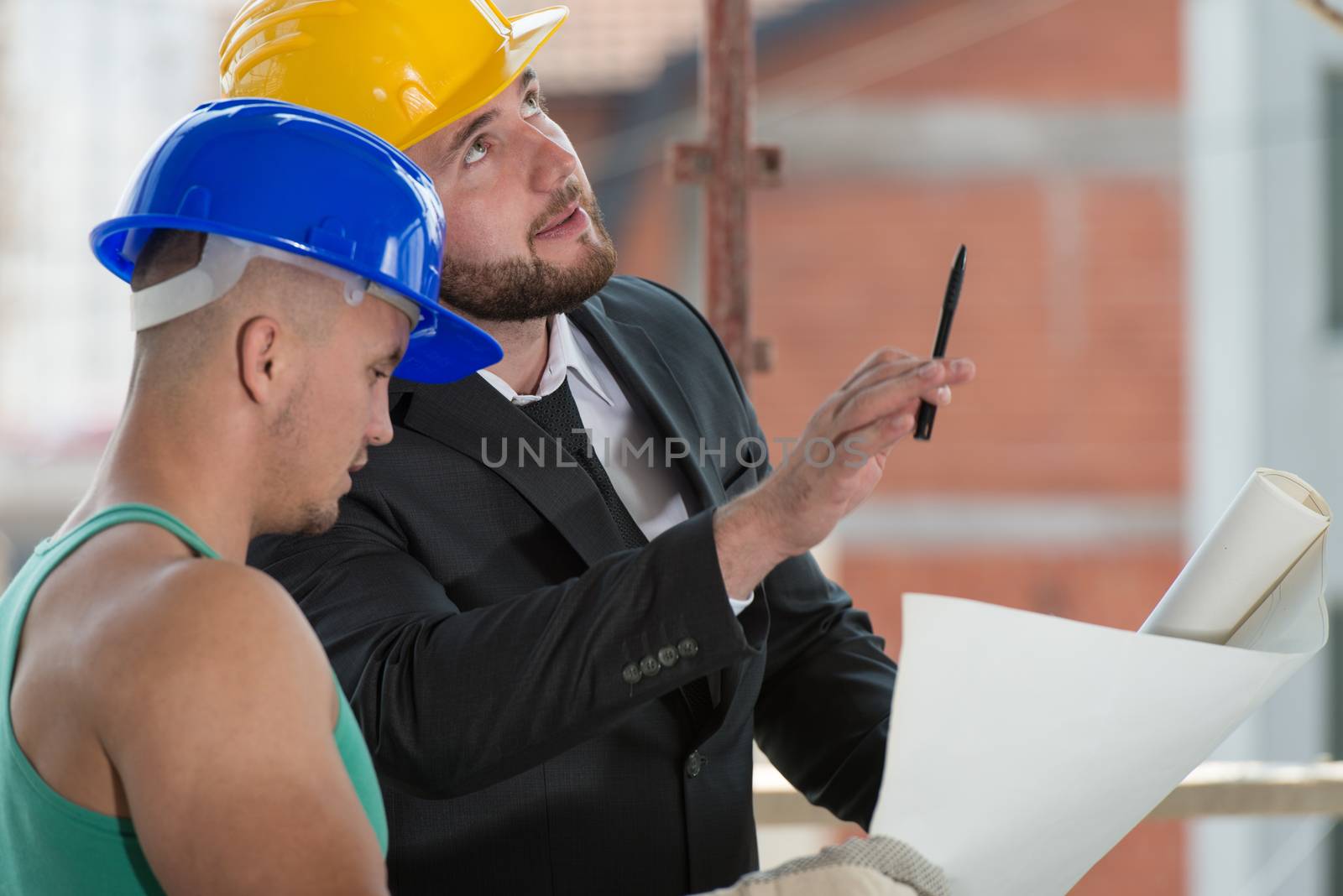 Businessman Showing Industrial Worker At Construction by JalePhoto