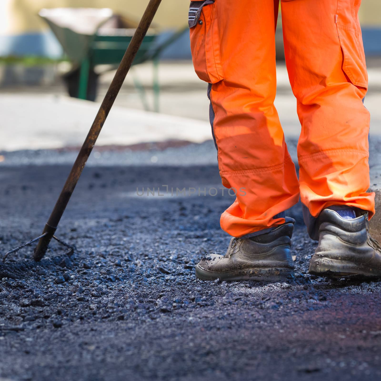 Construction workers during asphalting road works wearing coveralls. Manual labor on construction site.