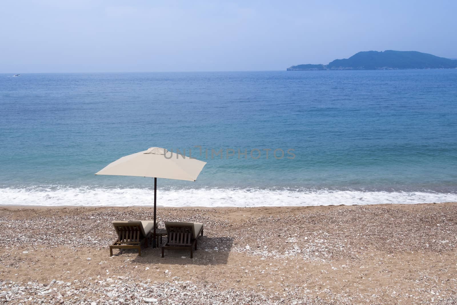 two sunbeds under sunshade on the empty sand beach