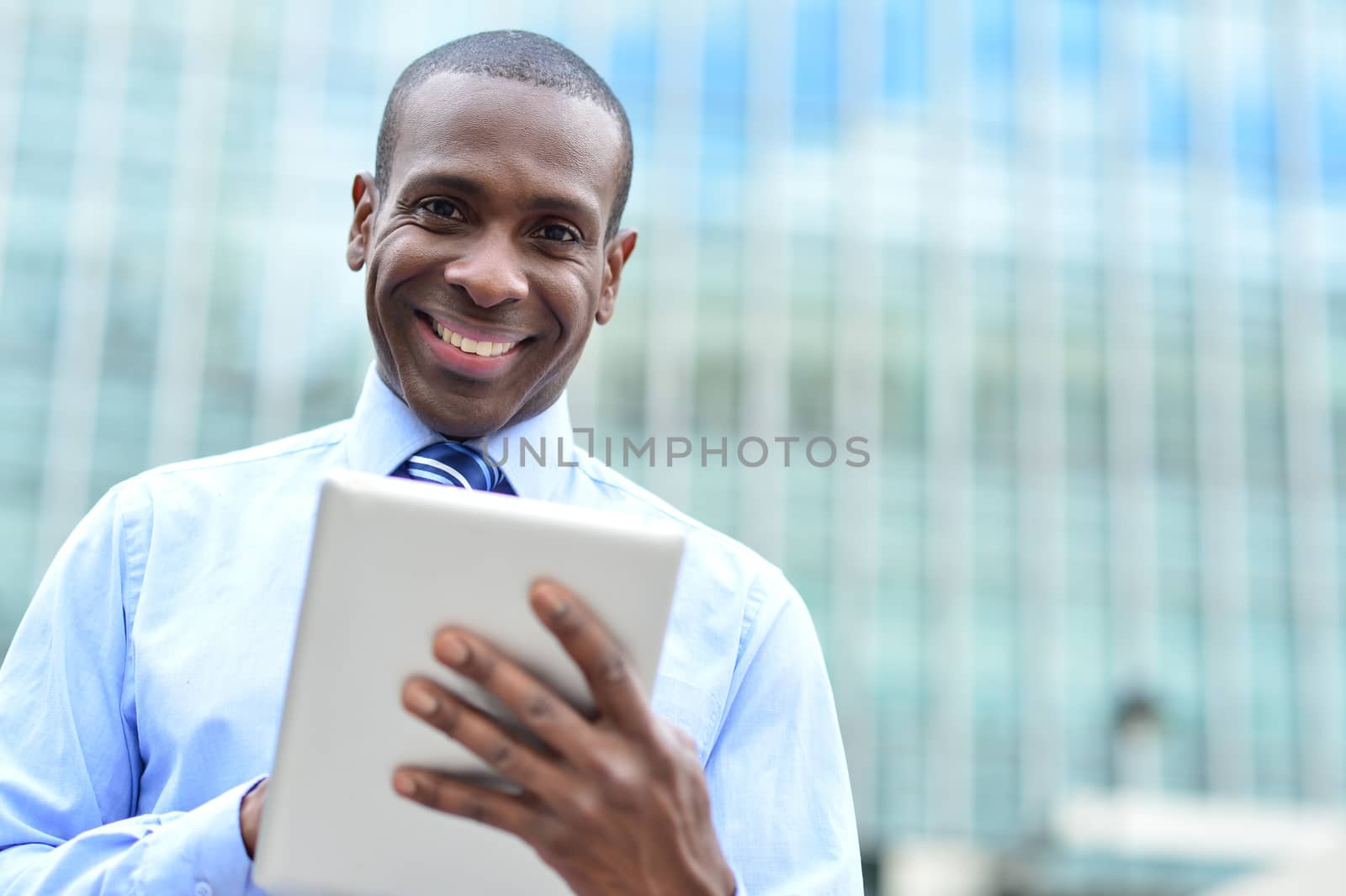 Smiling businessman posing outdoors with a tablet