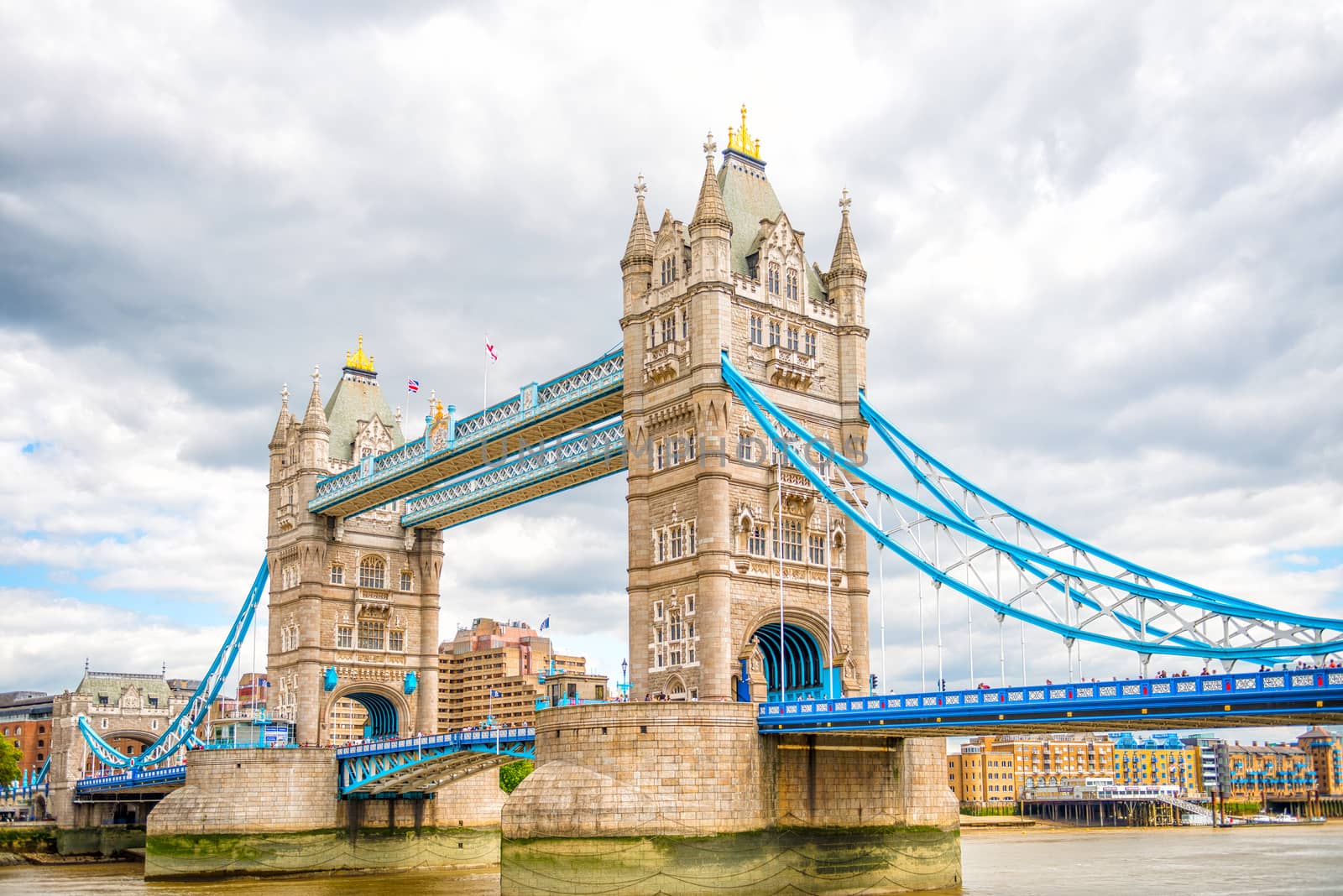 London Tower Bridge is a combined bascule and suspension bridge in London which crosses the River Thames. It is close to the Tower of London, from which it takes its name, and has become an iconic symbol of London.

Built during 1886 – 1894, the bridge consists of two towers tied together at the upper level by means of two horizontal walkways, designed to withstand the horizontal forces exerted by the suspended sections of the bridge on the landward sides of the towers. The vertical component of the forces in the suspended sections and the vertical reactions of the two walkways are carried by the two robust towers. 

The bascule pivots and operating machinery are housed in the base of each tower. The bridge's present colour scheme dates from 1977, when it was painted red, white and blue for Queen Elizabeth II's silver jubilee. Originally it was painted a mid-greenish-blue colour.

Photographed using Nikon D800E (36 megapixels) DSLR with AF-S NIKKOR 24-70 mm f/2.8G ED lens at focal length 34 mm, ISO 100. It is a High Dynamic Range (HDR) photograph.