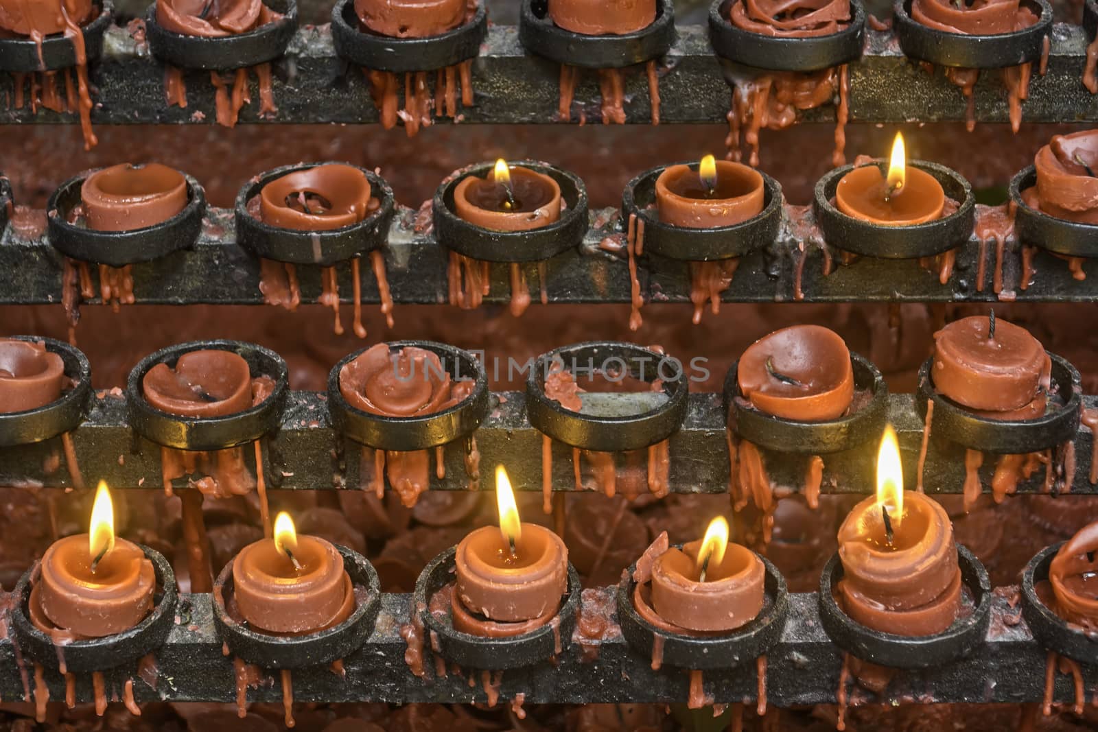 Lit and unlit red little candle offerings of people for their loved ones and prayer requests