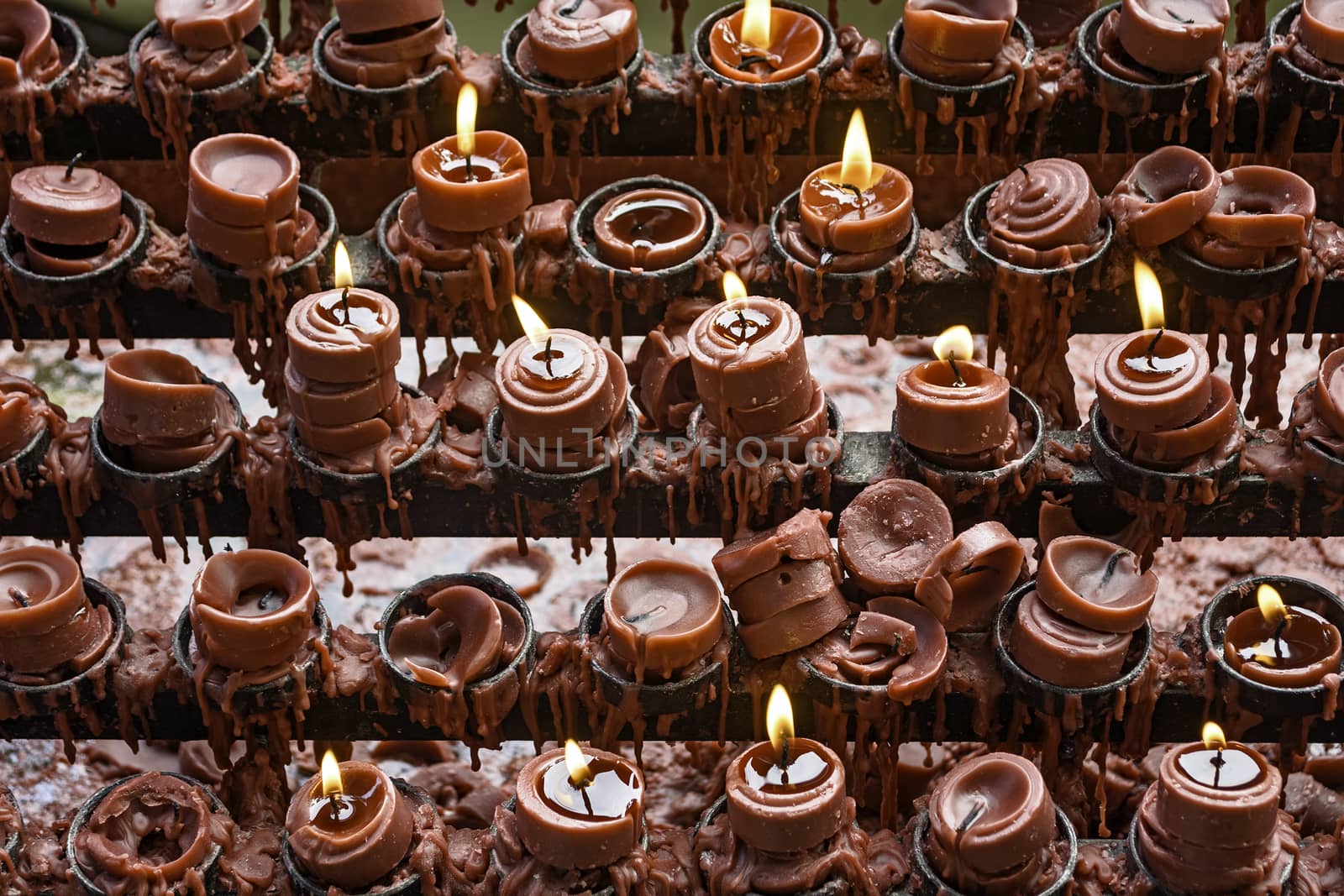 Lit and unlit red little candle offerings of people for their loved ones and prayer requests