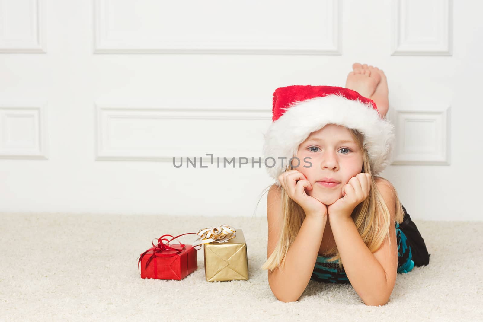 Girl in a Christmas cap lies outside the packed gifts