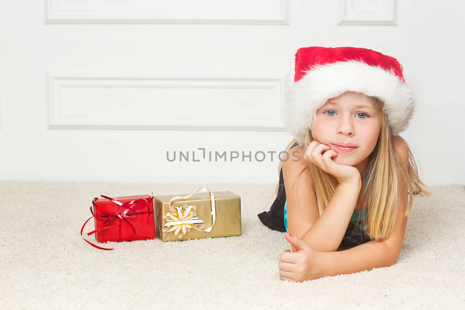 Girl in a Christmas cap lies outside the packed gifts