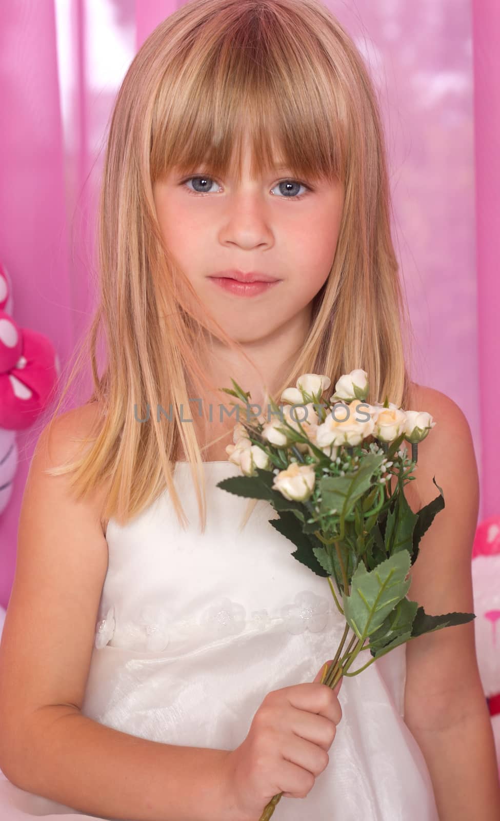 Beautiful tender girl in white festive dress holds bouquet of flowers. Over pink background.