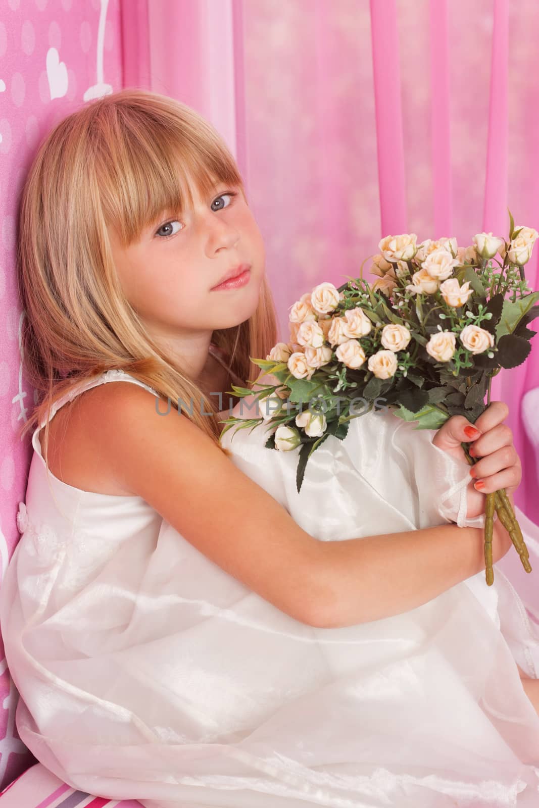 Beautiful tender girl in white festive dress holds bouquet of flowers. Over pink background.