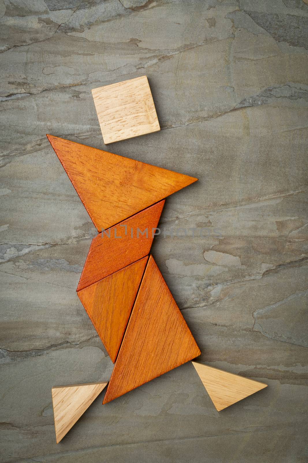 abstract figure of a female dancer built from seven tangram wooden pieces, a traditional Chinese puzzle game; slate rock background background, the artwork copyright by the photographer