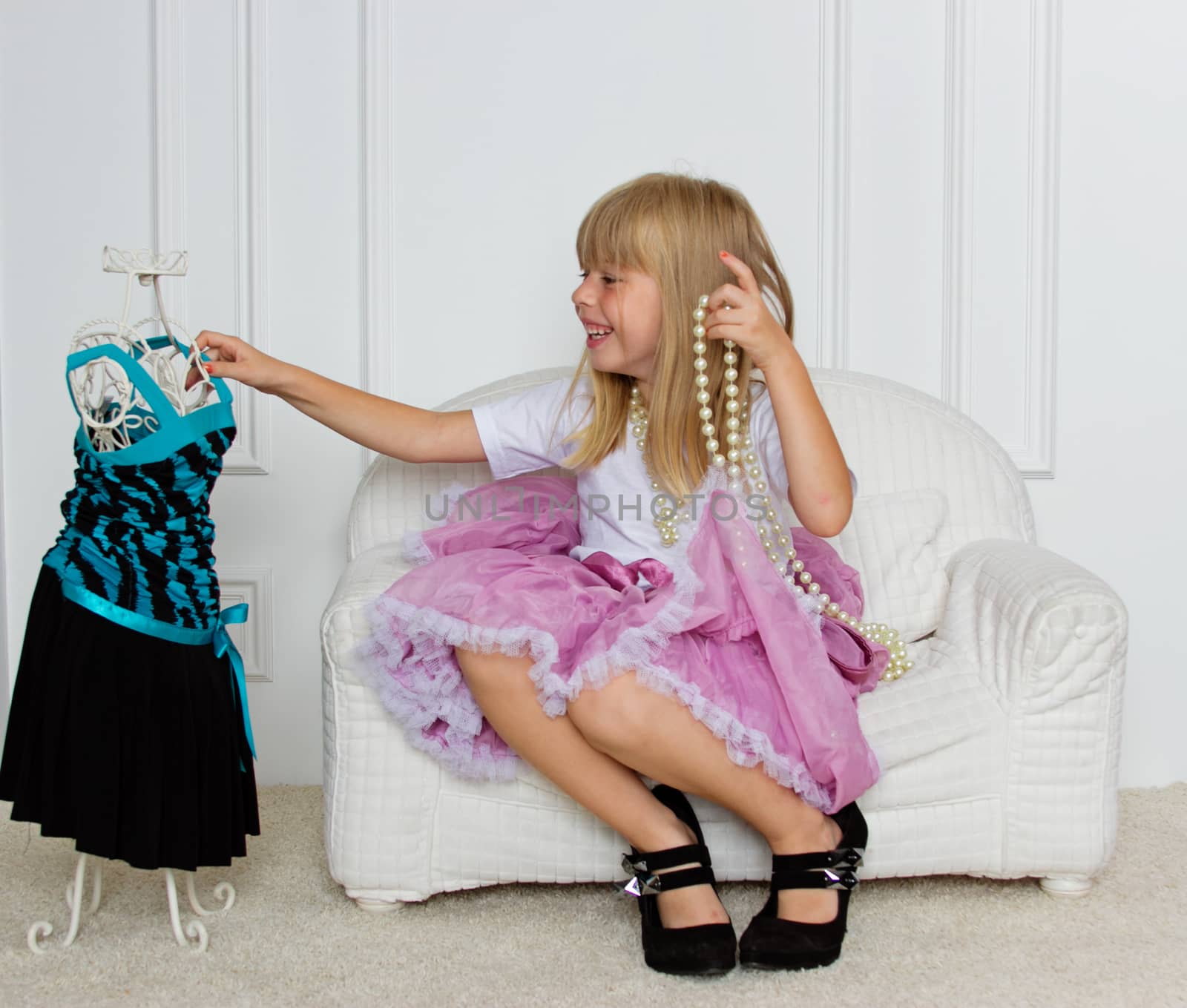 Girl in violet dress stands near mannequin in children store.