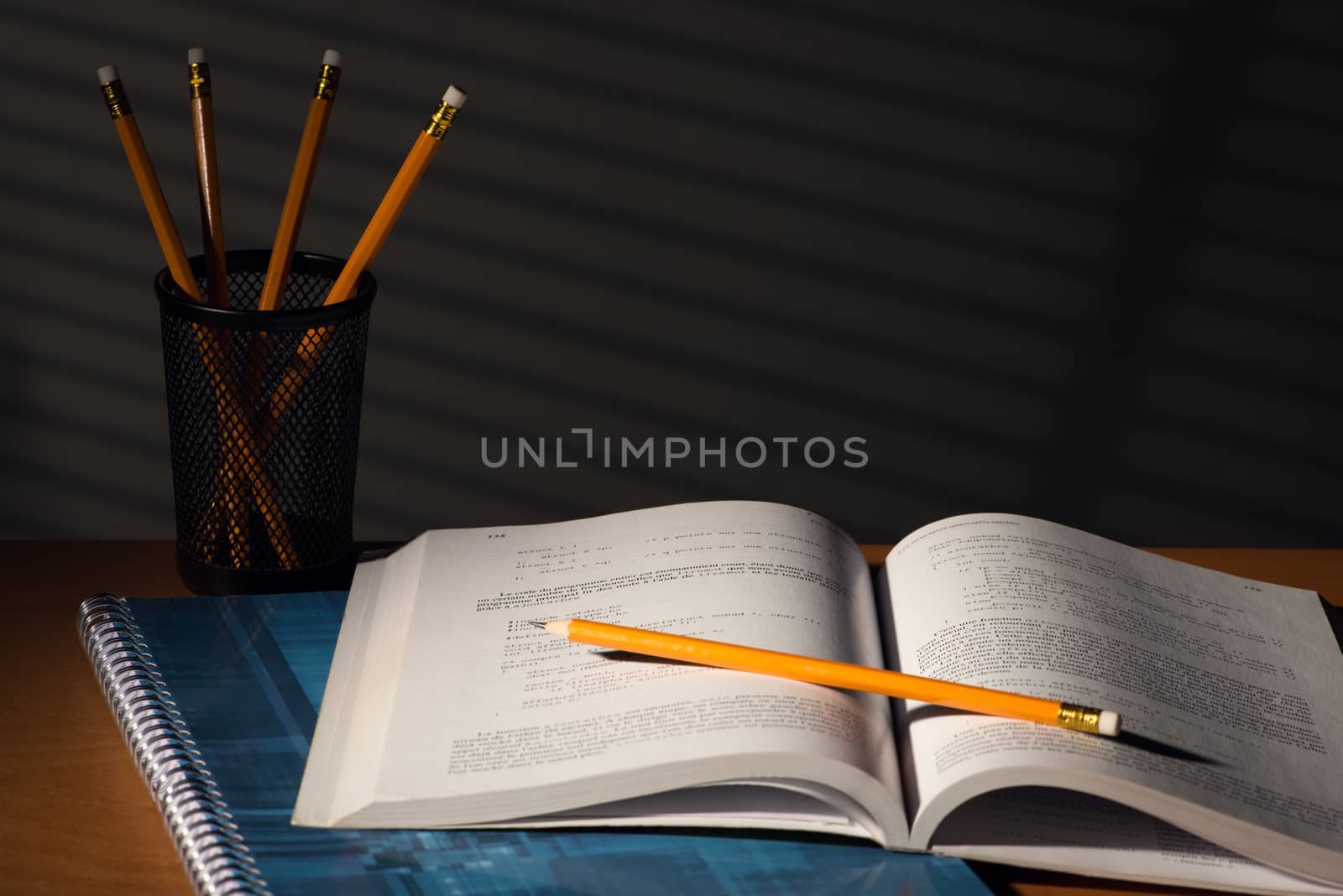 Desk with school book in night with light of blinds