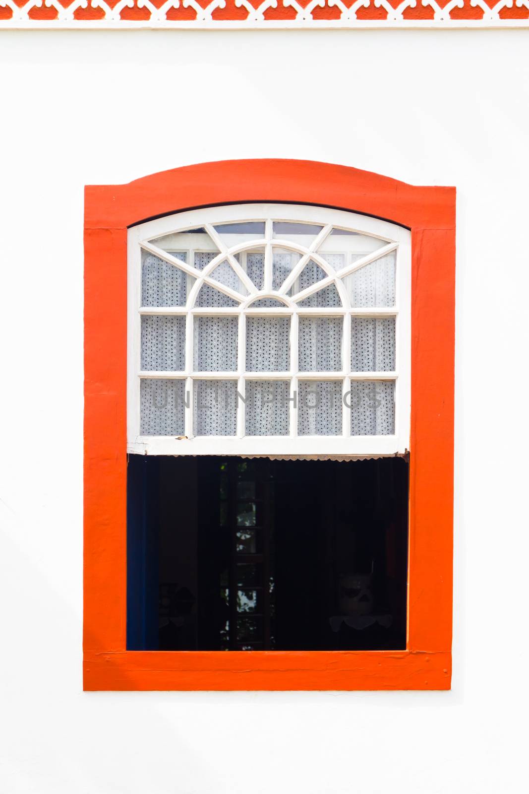 Decorative, colonial, red, vintage, window on a white wall in Paraty (or Parati), Brazil.