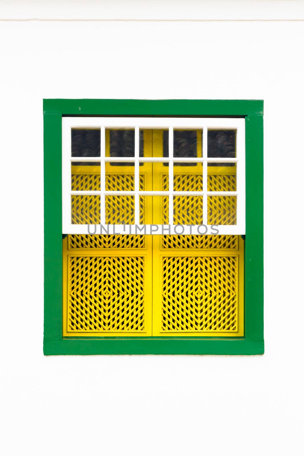 Decorative, colonial, green yellow, vintage, window on a white wall in Paraty (or Parati), Brazil.
