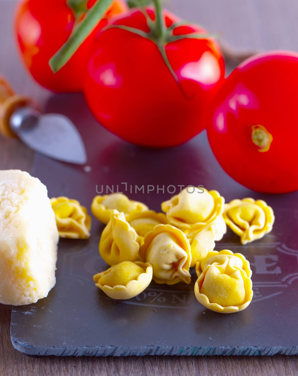 Agnolotti with cheese and tomatoes over black chopping board