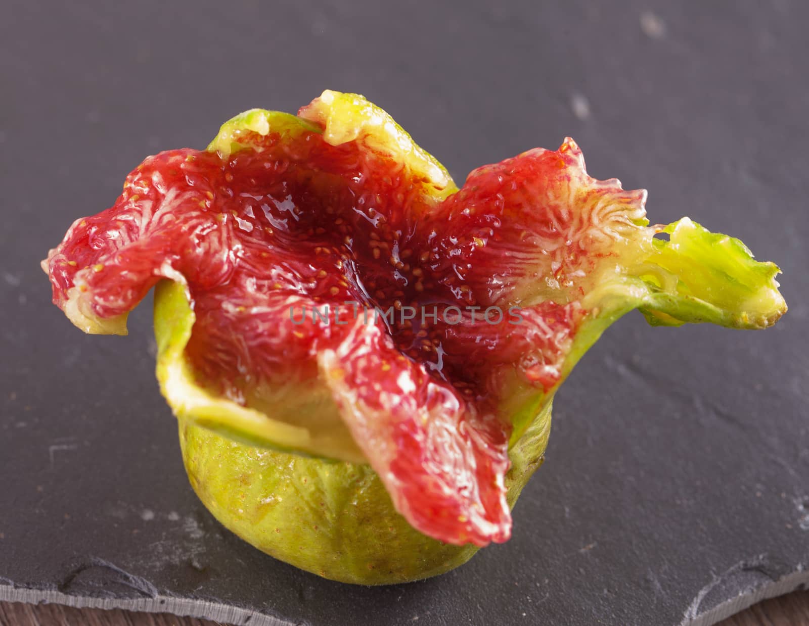 Open green fig over a black stone chopping board