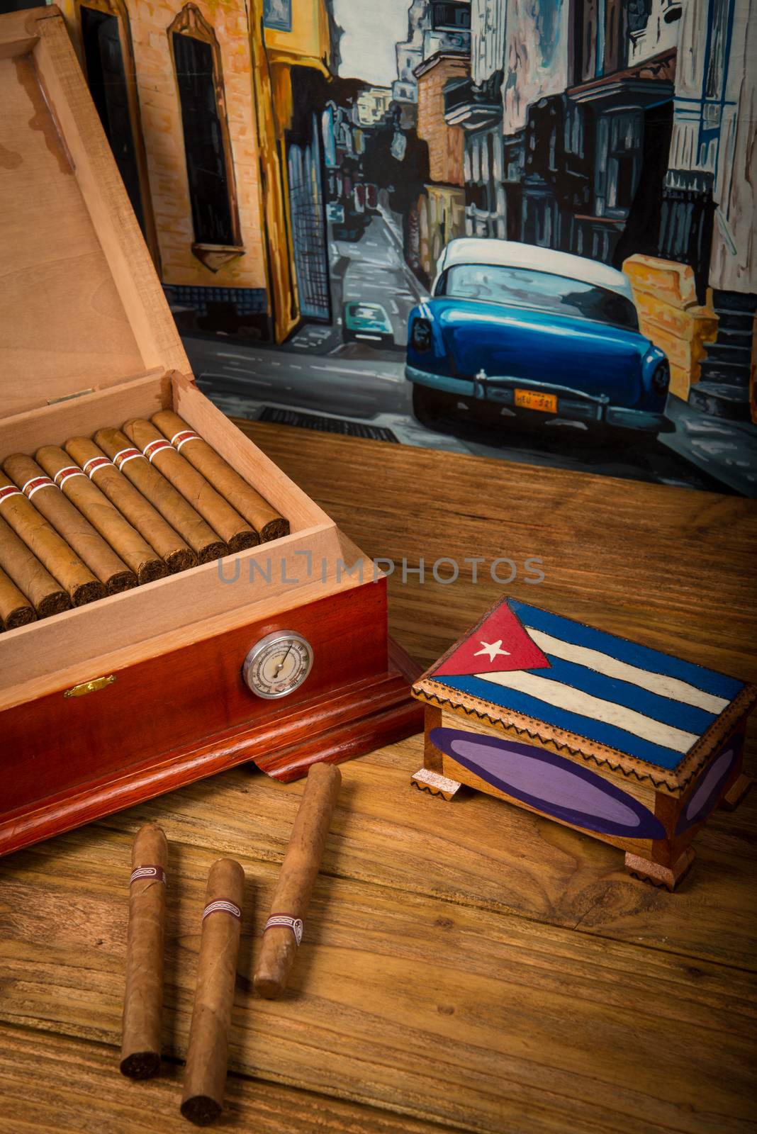 Cuban cigars and humidor with ashtray on rustic wooden table with Cuban painting of american old car in background