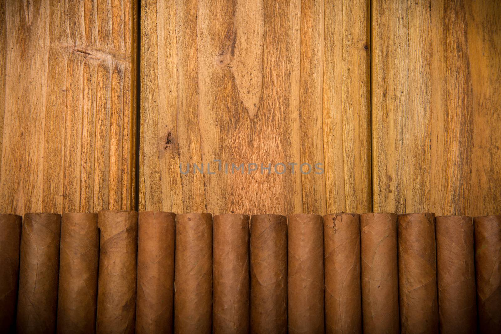Cuban cigars on rustic wooden table in line on the edge of background