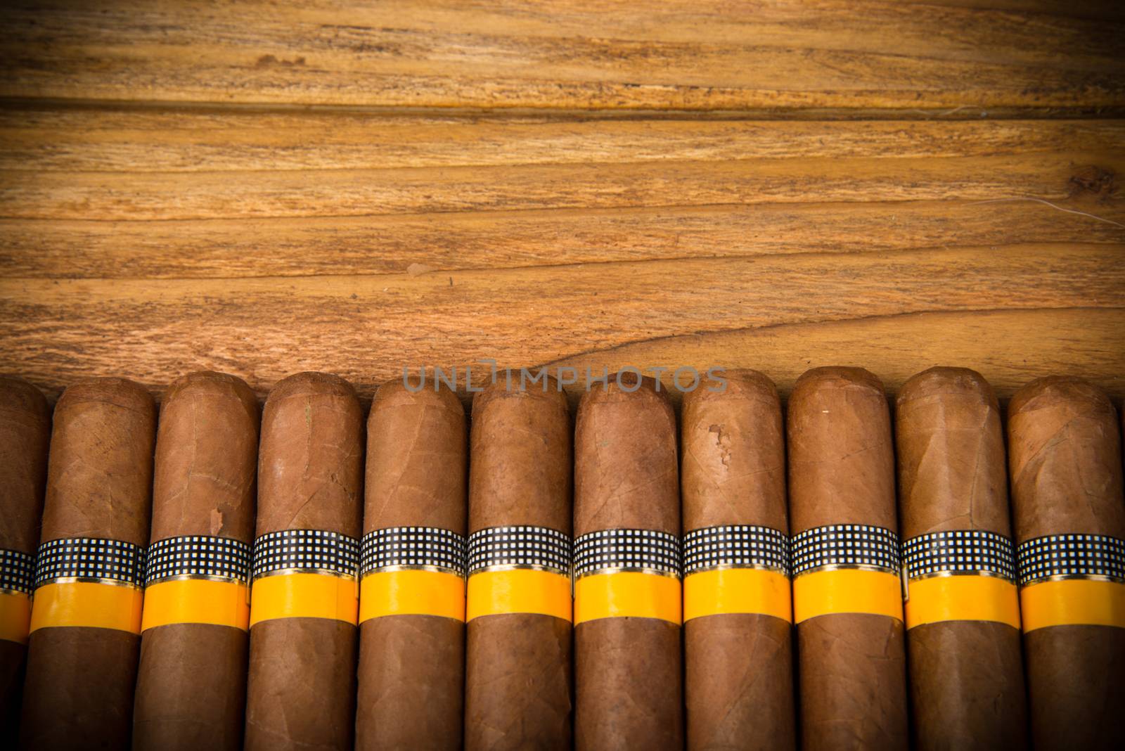 Cuban cigars on rustic wooden table in line on the edge of background