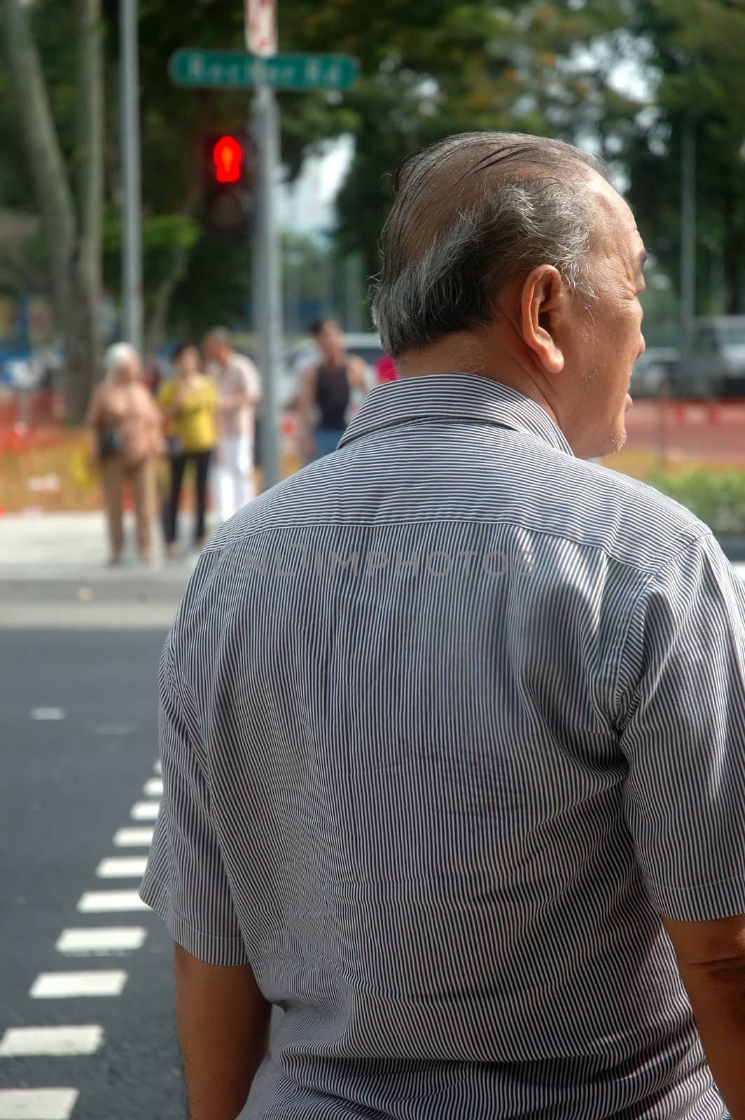Singapore, Singapore - January 18, 2014: Old man waiting for red light to get across the road.