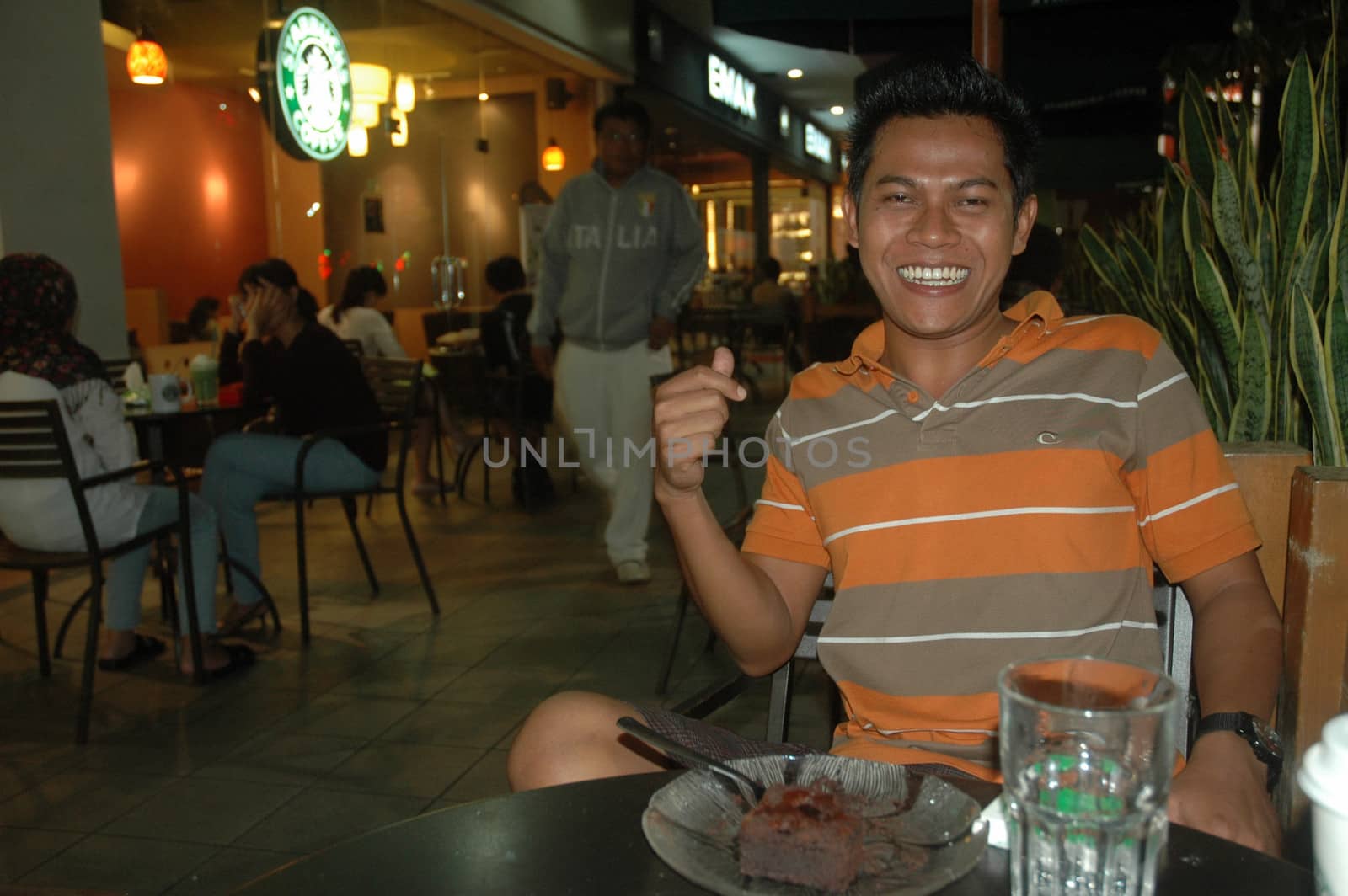 Bandung, Indonesia - July 2, 2011: Young man sit down on chair beside starbuck cafe.