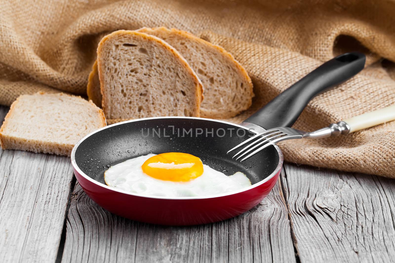 Fried egg in a frying pan, on an old wooden table