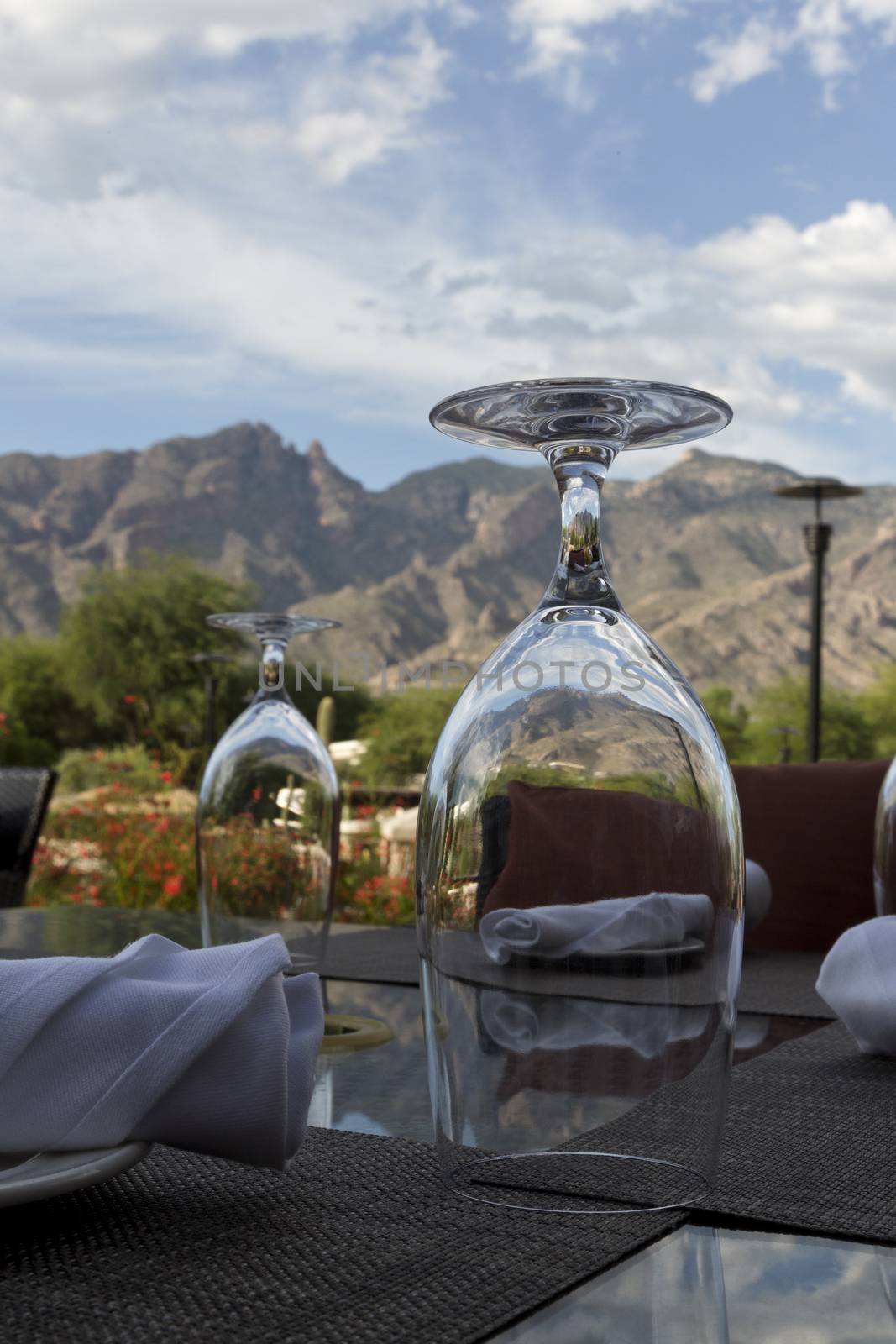 Water lasses on patio table in foreground of mountains and sky view are elements in relaxing, natural beauty.  Peaks are Catalina Mountains in Tucson, Arizona.  