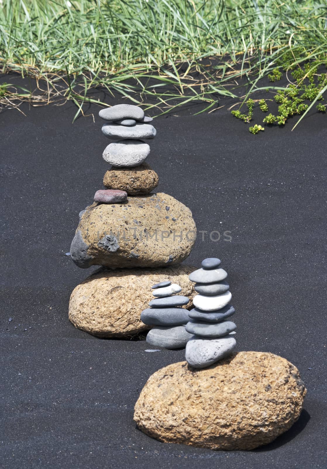 Small stacked rocks stacked on remote black sand beach in Iceland; vertical image with copy space; 