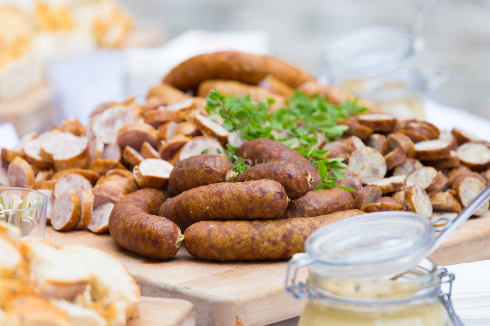 Dry sausage cold cuts. A variety of dry cold smoked meat products with herbs and mustard and  horseradish spreadon a wooden cutting board. 