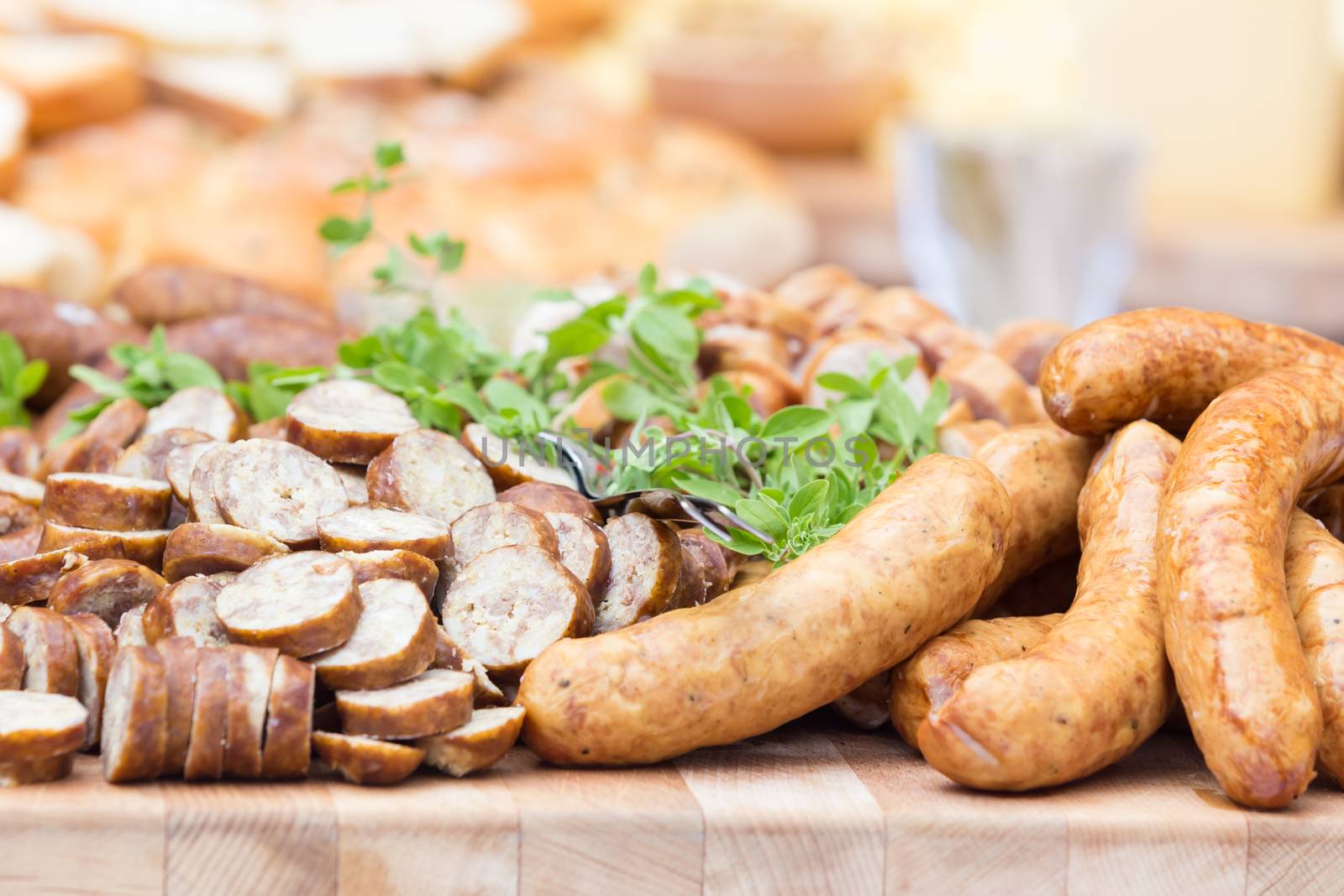 Dry sausage cold cuts. A variety of dry cold smoked meat products with herbs and mustard and  horseradish spreadon a wooden cutting board. 