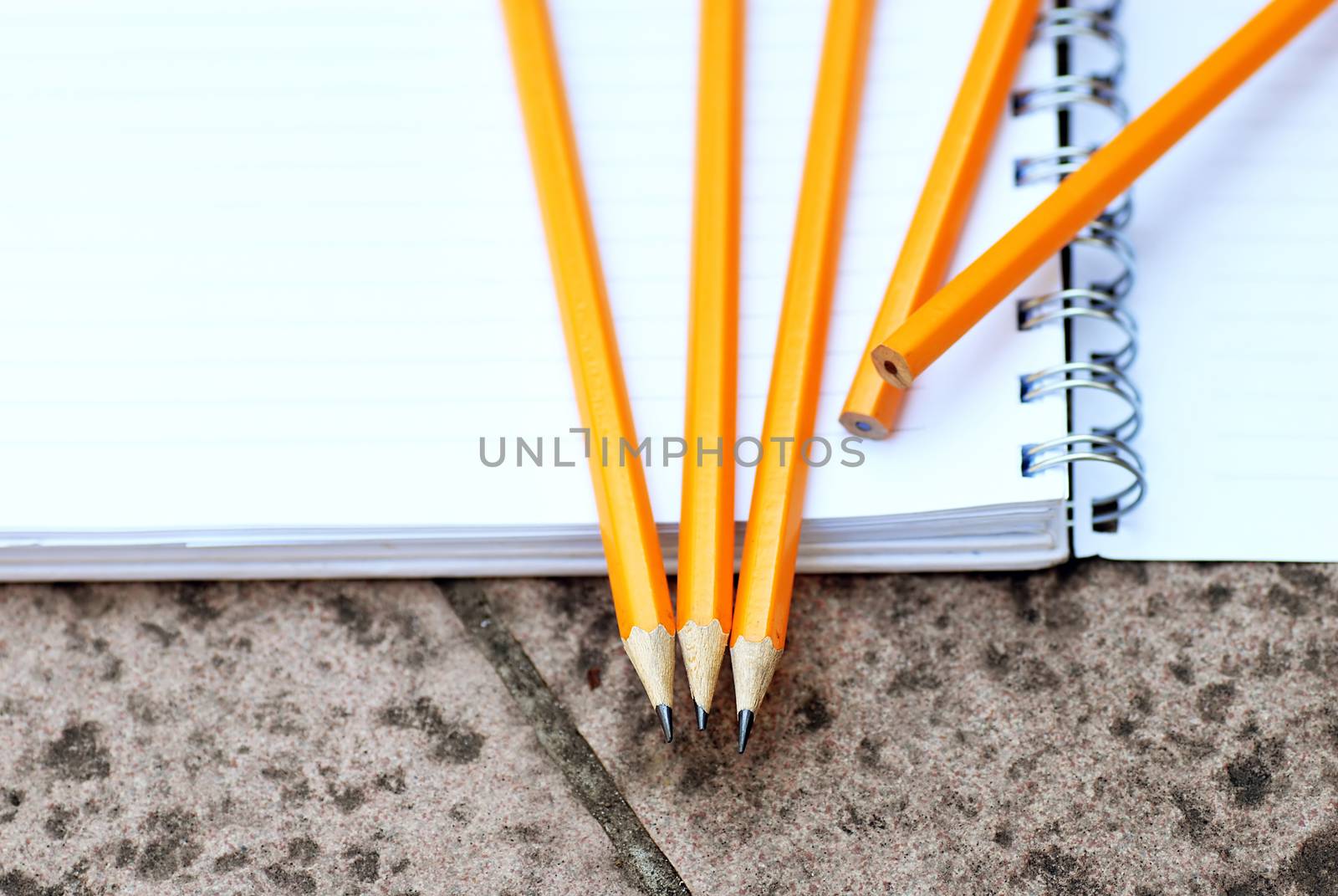 wooden graphite pencils on white open notebook closeup