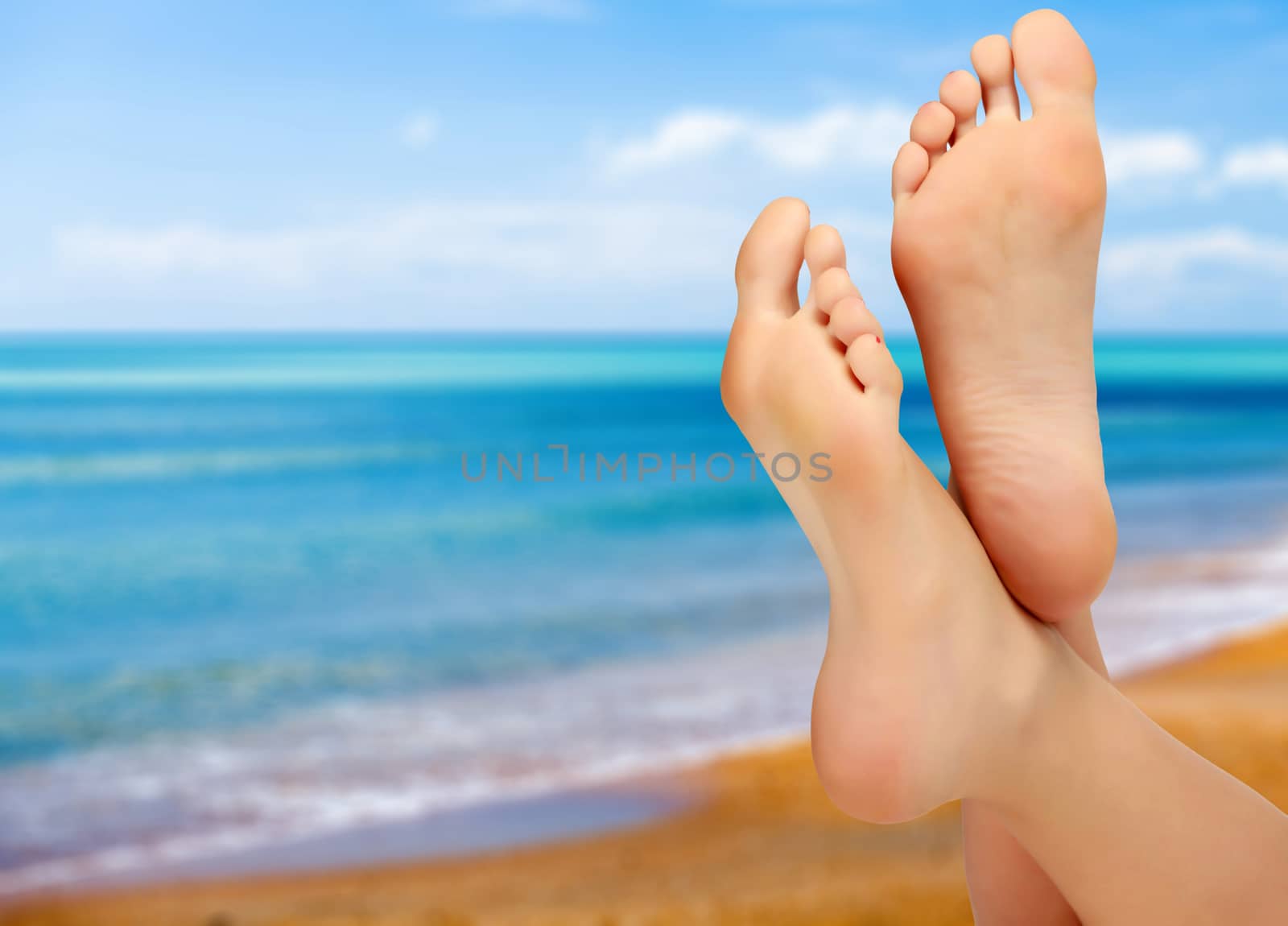 Female feet against blue sea and sky