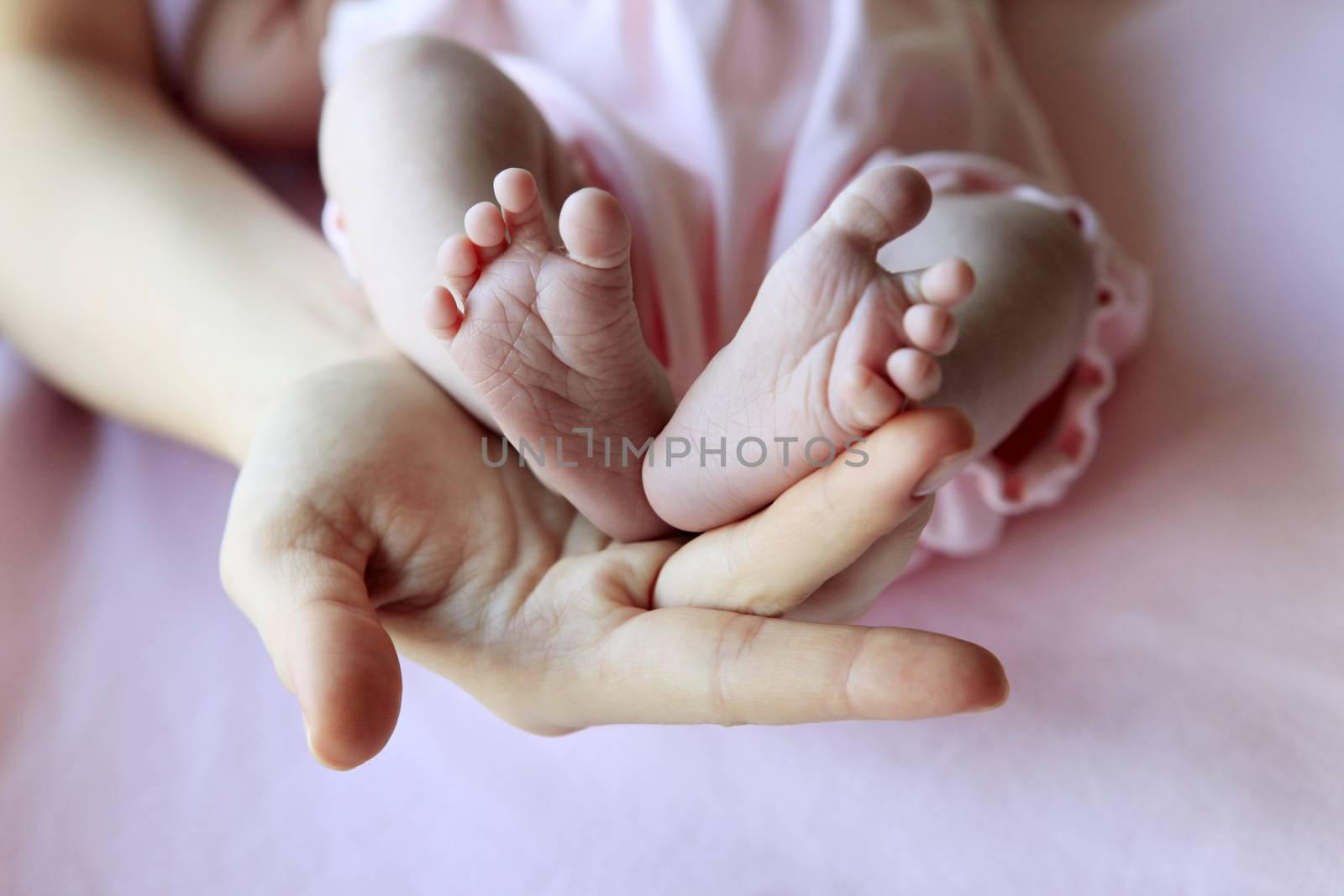 Parent hand hold baby girl legs