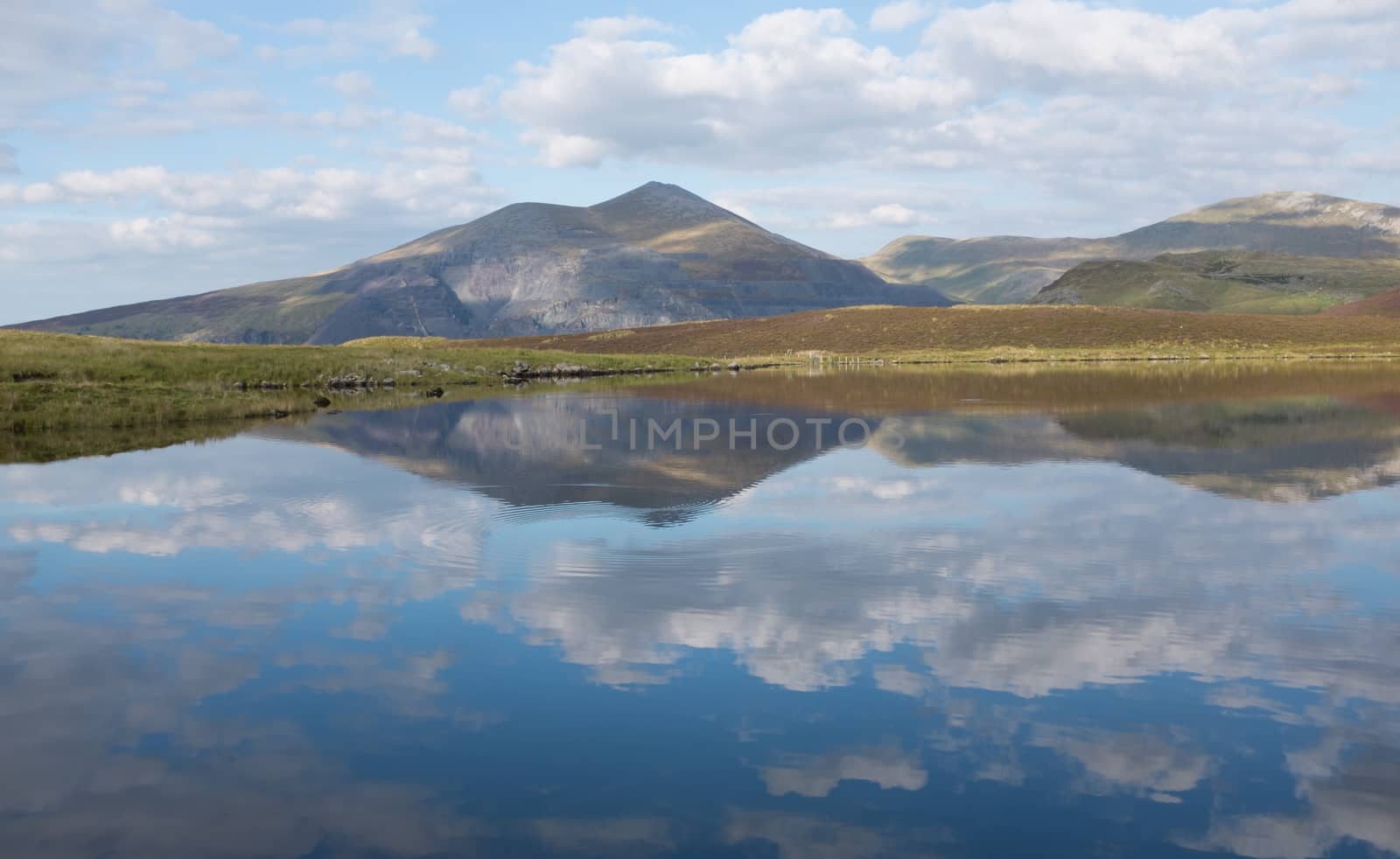 Llyn Dwythwch with the reflections of the sky and the mountains Elidir fawr and Y garn, Snowdonia national park, Wales, UK.
