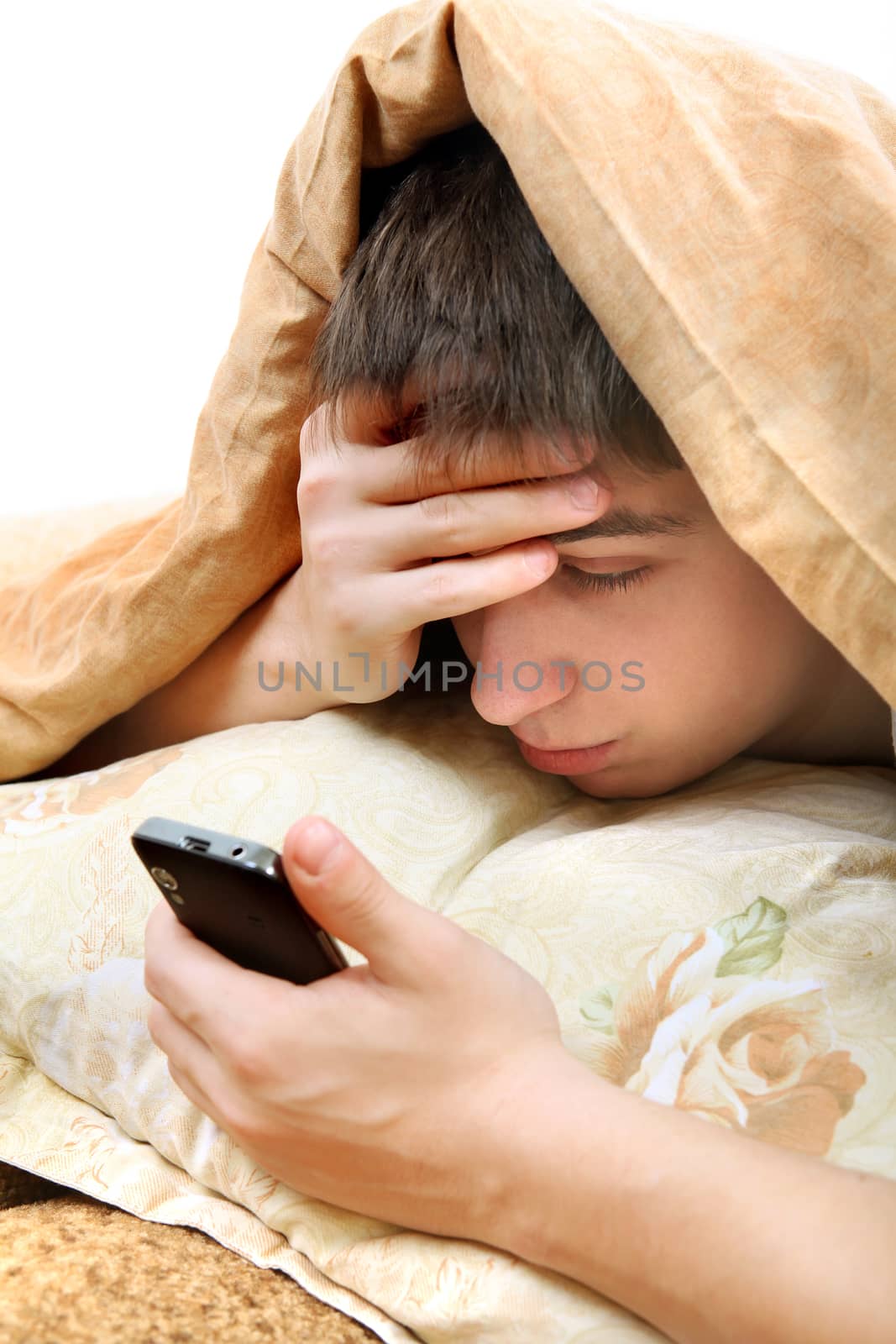 Sad Teenager with Cellphone under Blanket at the Home