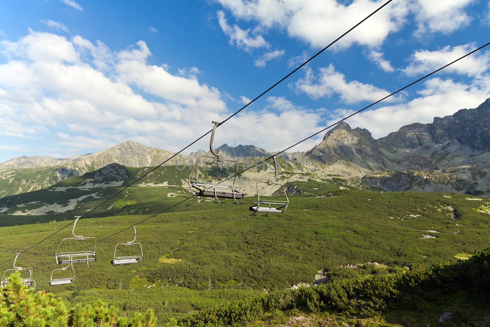 view on mountains in summer with ski lift on blue sky background