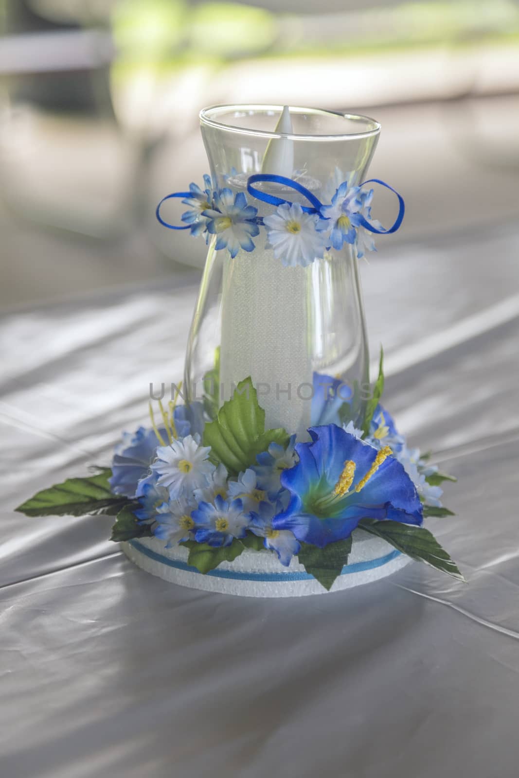 Candle in glass centerpiece. Cute blue flowers and ribbons adorn the glass. 
