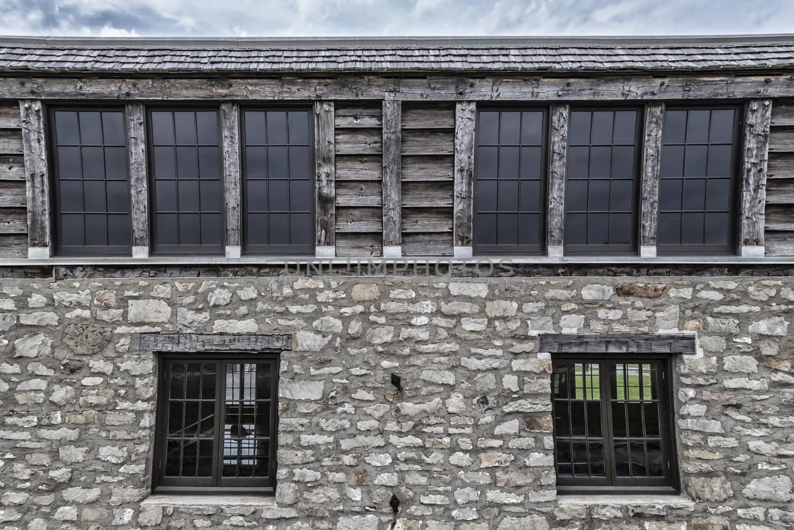 Row of dark paned windows in a historic cobblestone building. 