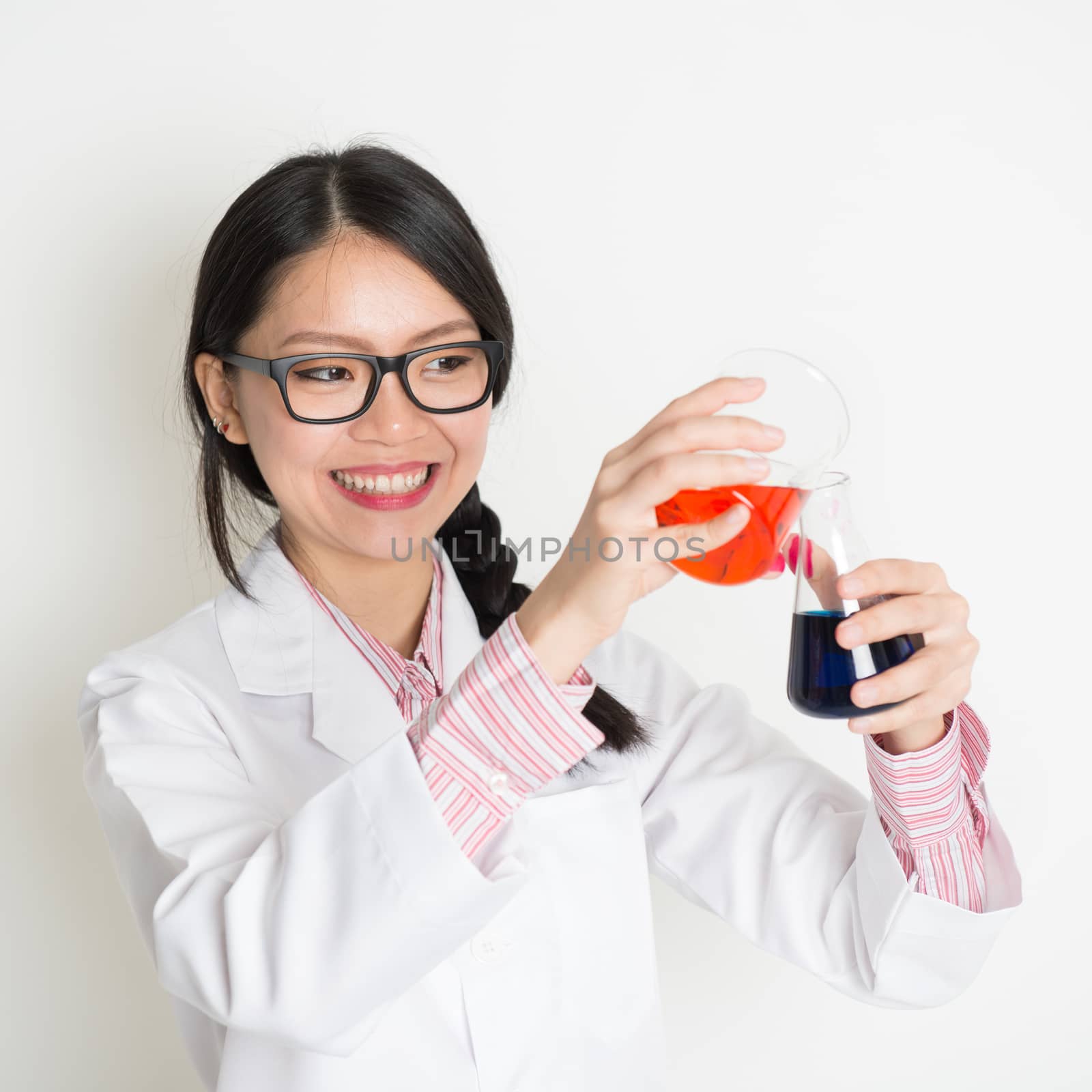 Asian girl biochemistry student doing liquid sample test analysis, on plain background.