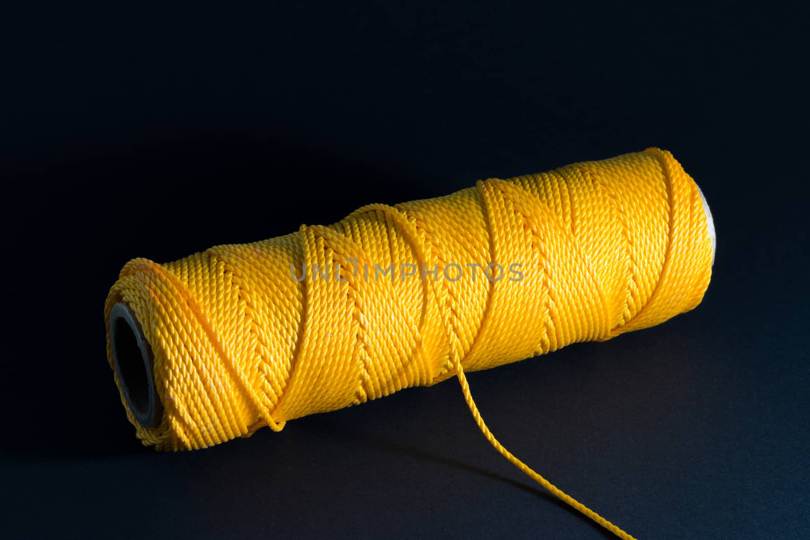 Thread spool with yellow thread on dark background