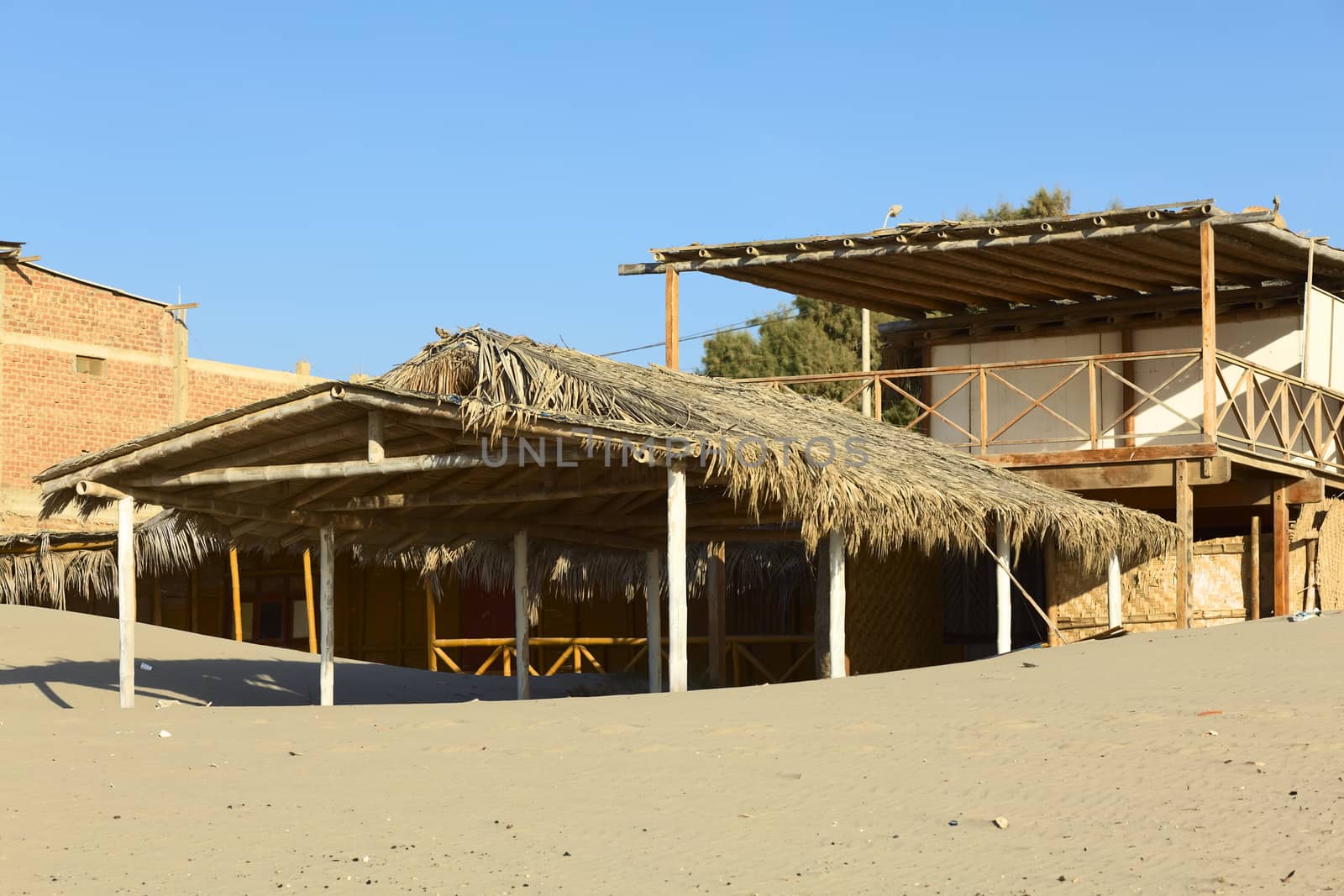 LOS ORGANOS, PERU - AUGUST 30, 2013: Thatched roof bamboo construction on the sandy beach on August 30, 2013 in Los Organos, Peru. Los Organos is a small beach town in Northern Peru, close to the popular town of Mancora. 