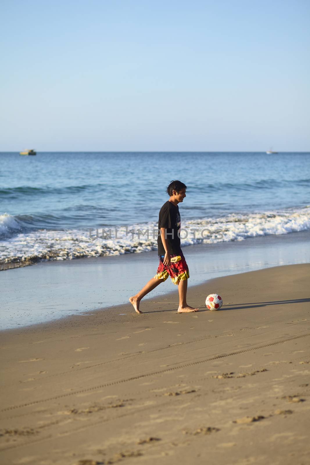 LOS ORGANOS, PERU - AUGUST 30, 2013: Unidentified young man playing football on the sandy beach on August 30, 2013 in Los Organos, Peru. Los Organos is a small beach town in Northern Peru.