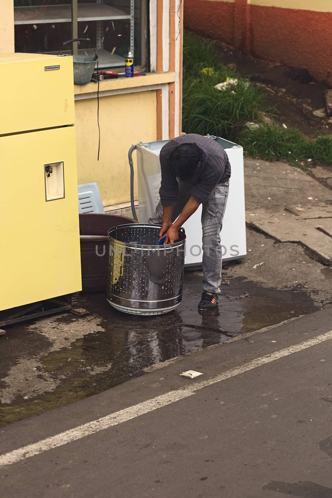 TUNGURAHUA, ECUADOR - MAY 12, 2014: Unidentified person cleaning a washing drum with water and brush on the roadside along the road between Ambato and Banos on May 12, 2014 in Tungurahua Province, Ecuador