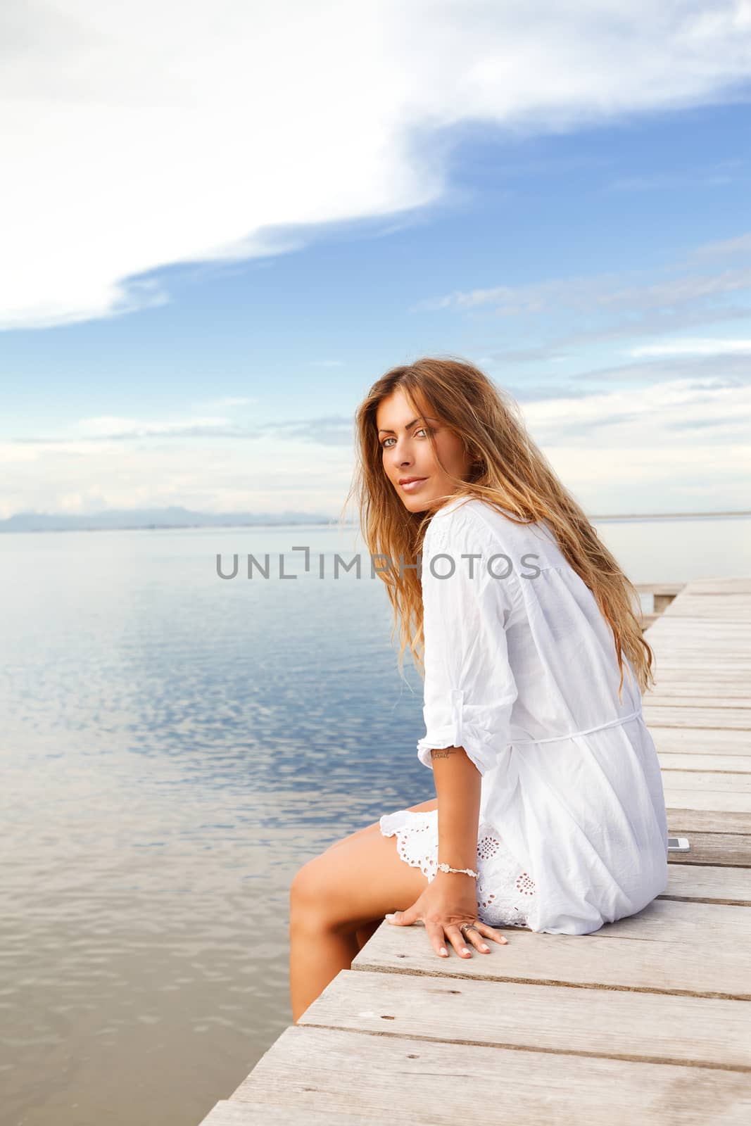 Portrait of Young smiling woman in white clothes on a pier